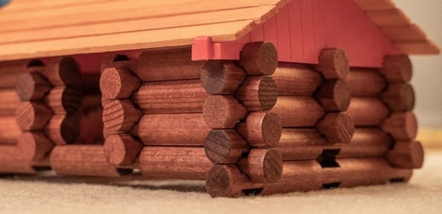 A partially constructed log cabin made from Lincoln Logs, demonstrating how these wooden pieces come together to form rustic, sturdy structures.