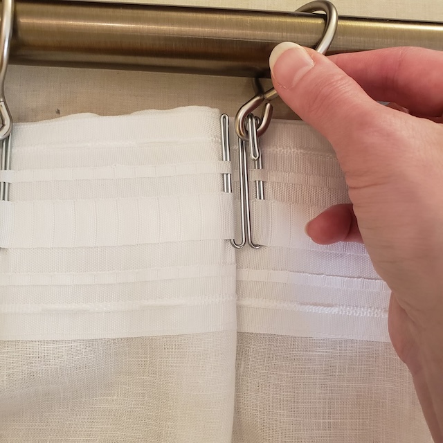 The vintage stainless steel curtain hooks in action, used to hold a sheer curtain on a metal rod, demonstrating their ease of use