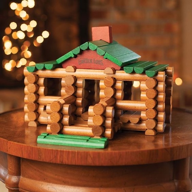 A fully constructed Lincoln Logs wooden cabin, complete with a green roof, capturing the essence of this iconic children's toy from the past