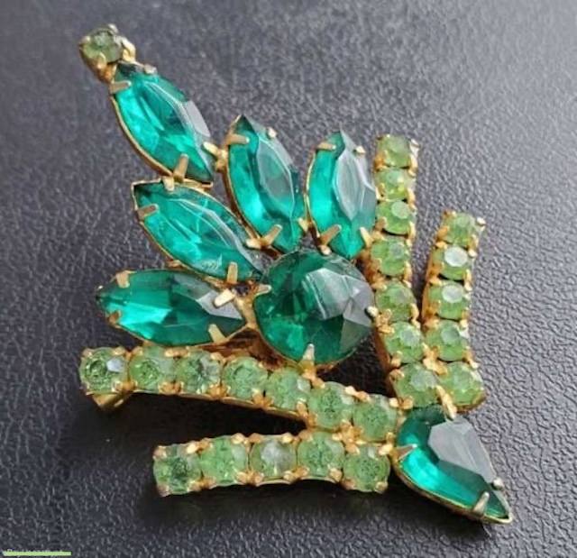 A stunning piece of Juliana D&E vintage jewelry featuring vibrant green rhinestones arranged in a captivating floral design, showcasing the brand’s signature craftsmanship.