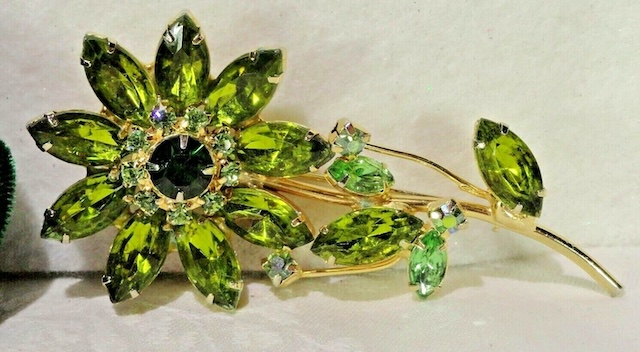 This elegant brooch from the Juliana D&E vintage jewelry collection highlights the beauty of green marquise-cut rhinestones, expertly arranged to create a blooming flower.