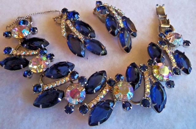 A dazzling set of Juliana D&E vintage jewelry, featuring a bracelet and earrings adorned with rich blue rhinestones and sparkling crystal accents, perfect for adding a touch of vintage glamour.