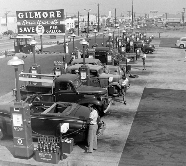 A bustling day at the Gilmore Gas Station in the 1940s. Cars line up for self-service gas at just 5 cents per gallon, showcasing the early days of a major cultural shift in American automobile life