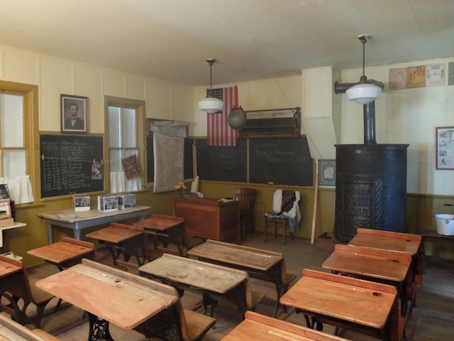 A 1930s classroom with wooden desks and chalkboards, reflecting discipline and patriotism in education