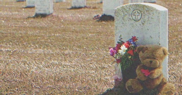 A lone teddy bear placed at the grave symbolizes the love and innocence lost too soon, as the mother wonders who left the heartfelt gift