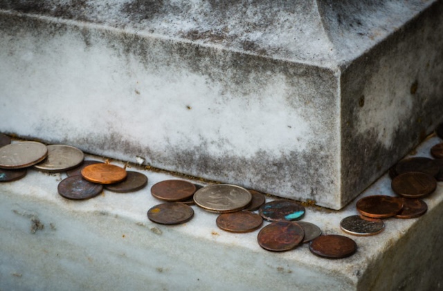 Coins of various denominations are left on this grave, each one symbolizing a different level of connection and remembrance