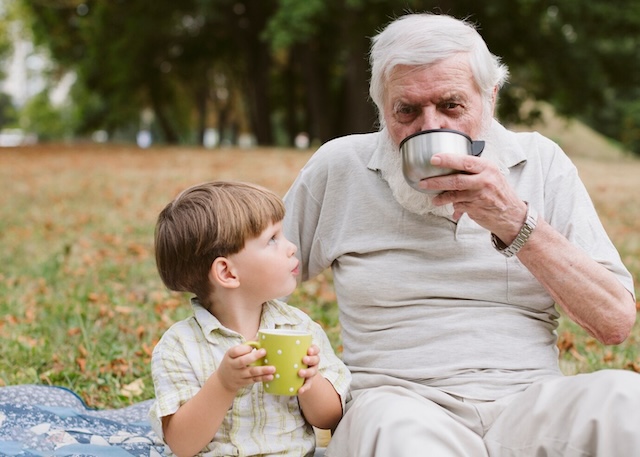 Enjoying a peaceful picnic together, the grandfather and grandson share a quiet afternoon, savoring each other's company