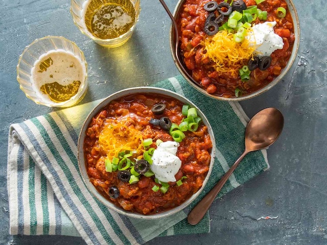 Topped with sour cream, cheese, olives, and green onions, this modern take on chili is both visually stunning and bursting with flavor