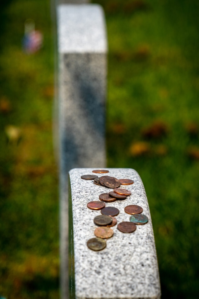 A stack of weathered coins, left by visitors, represents a long-standing tradition of paying tribute to the departed