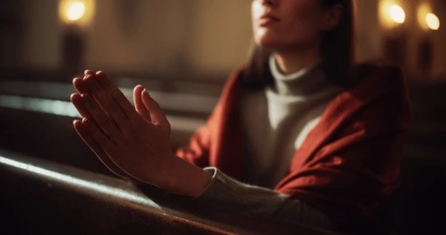 Praying hands in a quiet pew, emphasizing the spiritual focus that many believe should take precedence over outward appearances in church