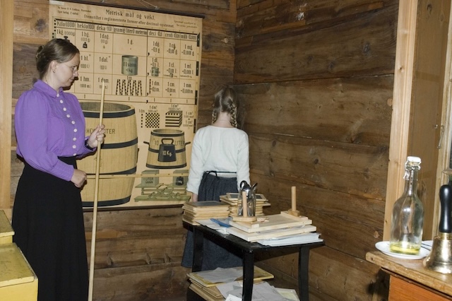 A classroom scene from the past, where a teacher uses a corner time-out as a form of discipline for a misbehaving student, with strict rules enforced through silence and isolation