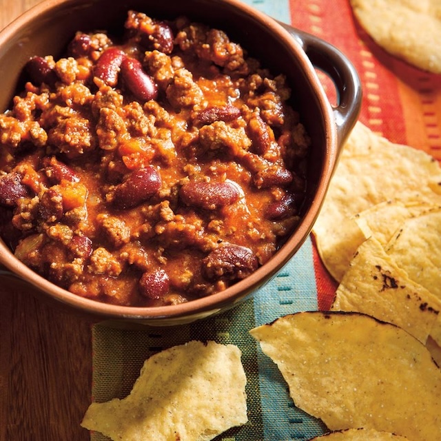 A bowl of chili packed with ground beef and kidney beans, ready to be scooped up with some crispy tortilla chips. Perfect for a cozy meal