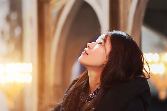 A woman looking upwards in contemplation, embodying a deeply personal connection to her faith, regardless of clothing