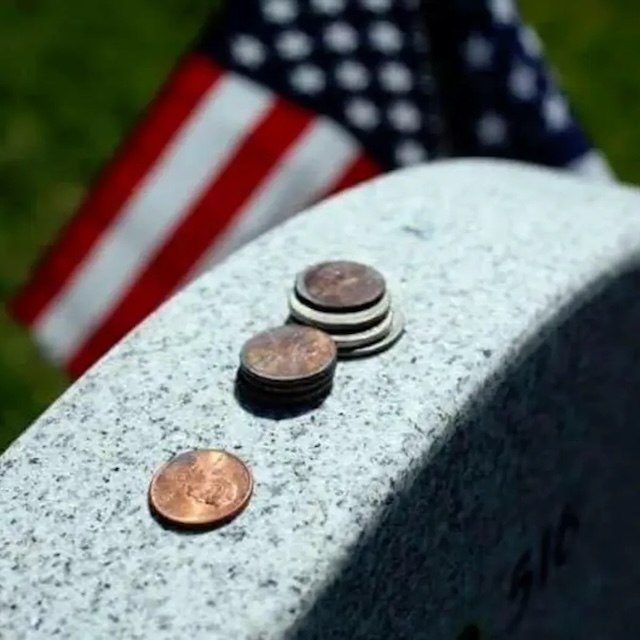 A powerful symbol of remembrance, coins left beside a flag honor veterans who served their country and those who visit to pay respects