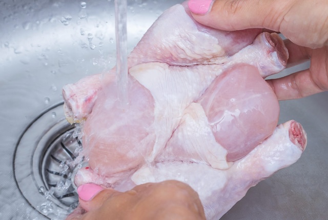 Rinsing a whole chicken under the tap—this traditional method may seem hygienic but can lead to contamination of kitchen surfaces