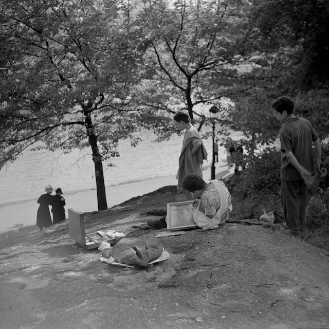 A group of park-goers taking in the peaceful atmosphere by the water, some quietly painting or sketching. The simple pleasures of creativity and tranquility in a bustling city environment