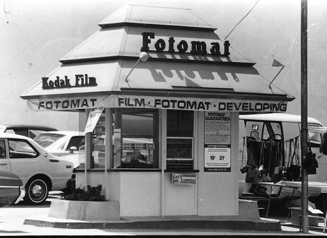 A black-and-white view of a Kodak Fotomat booth with "Drive-Thru" marking, reminding us of a quick yet non-instant era of photo developing