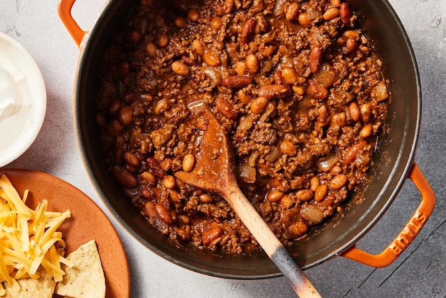 A pot of classic chili with a side of cheddar cheese and onions—a timeless favorite ready to be shared with family and friends