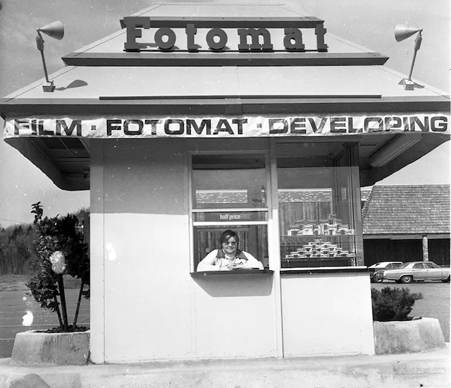  A friendly worker at a Kodak Fotomat booth, ready to develop your film and hand back printed photos