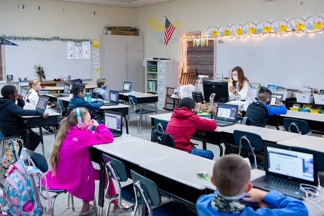 A contemporary classroom with students on laptops, highlighting the digital shift in education