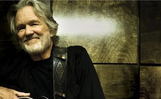 A serene portrait of Kris Kristofferson, guitar in hand, showcasing the legendary musician in his element—forever remembered as a storyteller and a trailblazer.