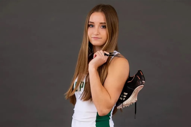 Shelby Daniele poses confidently with her running shoes, embodying her dedication as a college track star