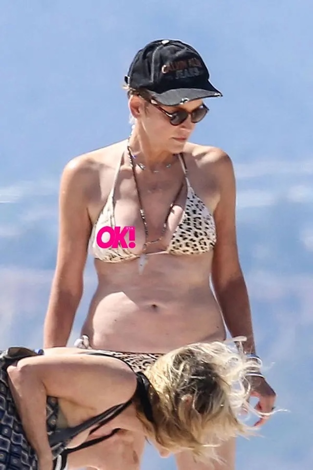 Sharon Stone walking along the beach in a leopard print bikini, radiating confidence and style at 66