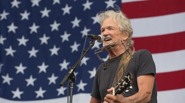 Kris Kristofferson singing in front of an American flag, a symbol of his love for country music and his outspoken activism throughout his life