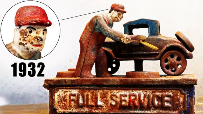 A closer look at the coin bank before restoration, with its original paint nearly gone and rust overtaking the intricate details of the full-service station scene.