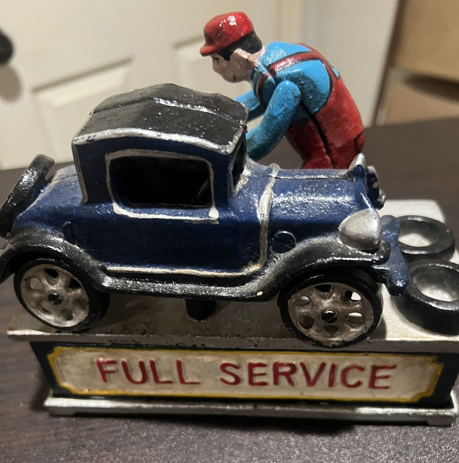 Fully restored and hand-painted, this vintage 1932 mechanical coin bank shines once more, showcasing its charming car and service station design.