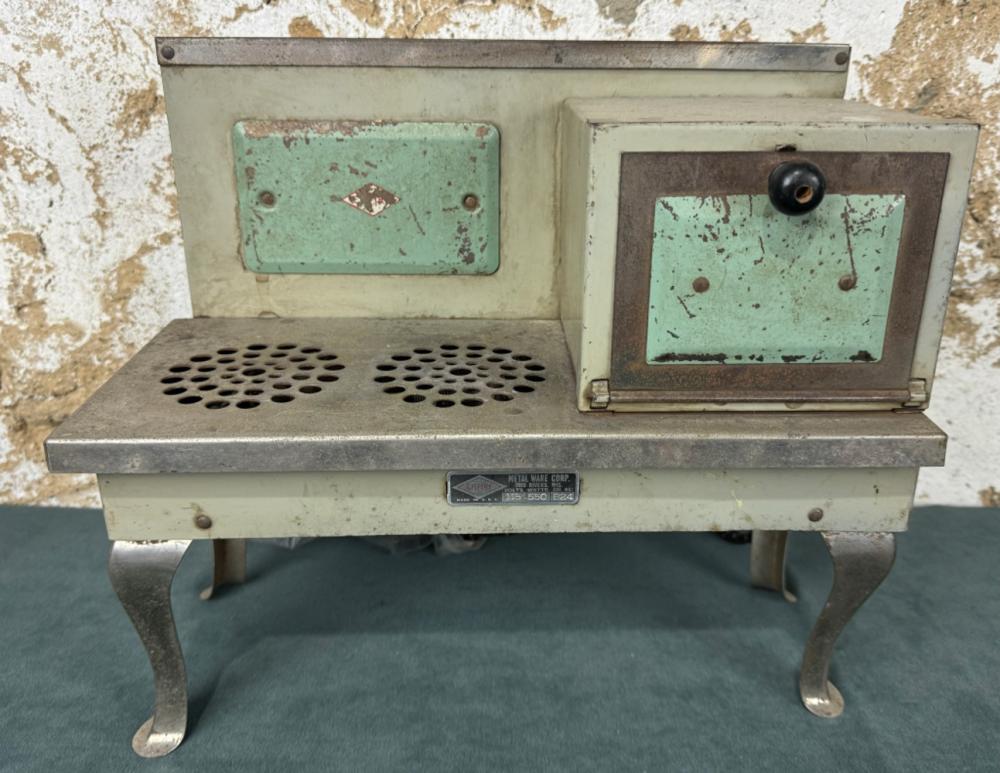 This vintage electric toy stove features its original mint green accents and simple design, a nostalgic nod to the functional toys of the 1930s that mirrored real household appliances.