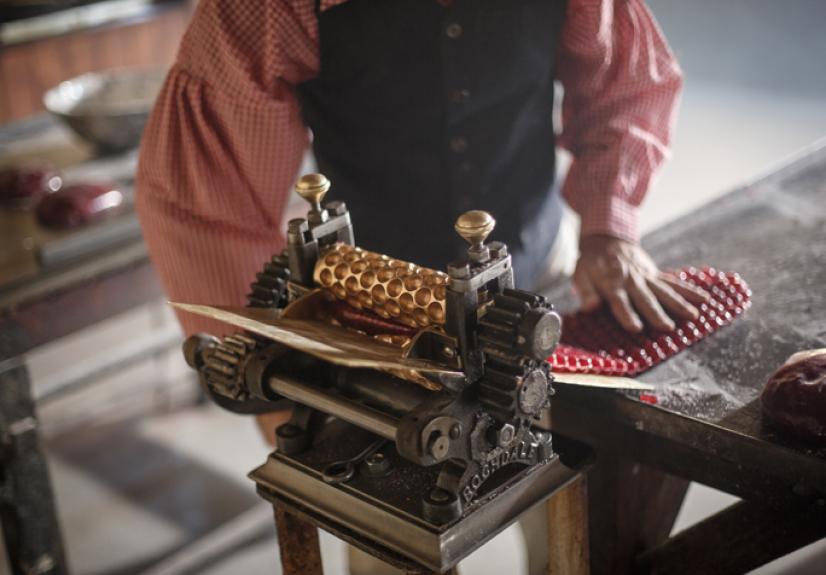 A candy maker uses a vintage roller to create classic candies, illustrating the age-old process of crafting sweets that still captivates enthusiasts today.