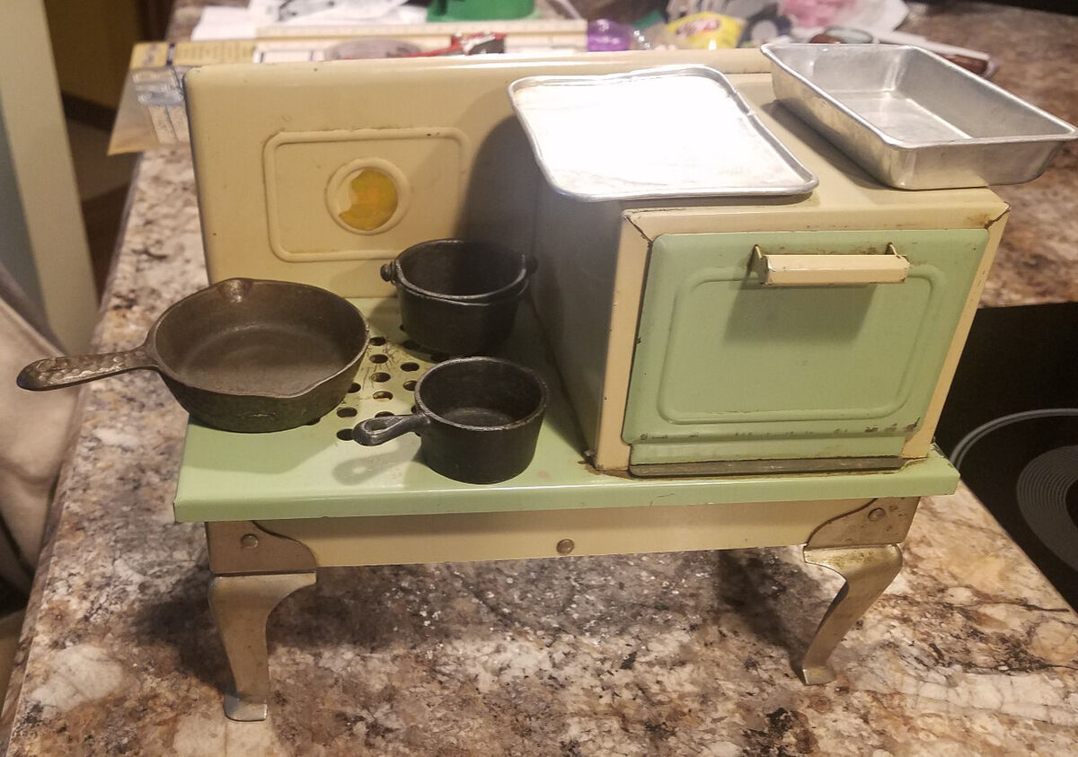 A well-loved 1930s Empire Metalware electric toy stove, complete with tiny pans and cooking trays, demonstrating the intricate detail and functionality these vintage toys offered children.