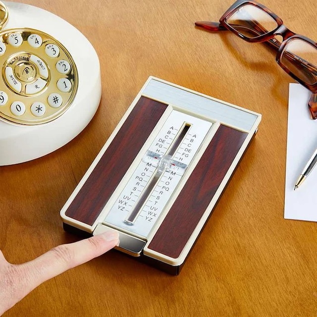 Set against a nostalgic backdrop, this vintage flip open address index sits next to an old-fashioned rotary phone, adding charm to any desk