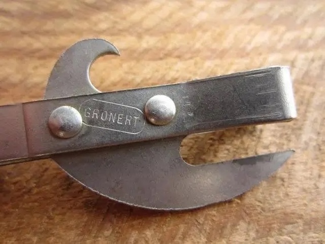 A detailed view of a vintage can opener with a sharp blade and sturdy design, once an essential tool in every kitchen