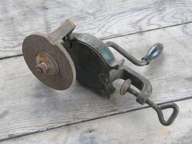 A side view of a hand crank grinder, showing its simple yet effective mechanism designed to hold and rotate the grinding stone for sharpening