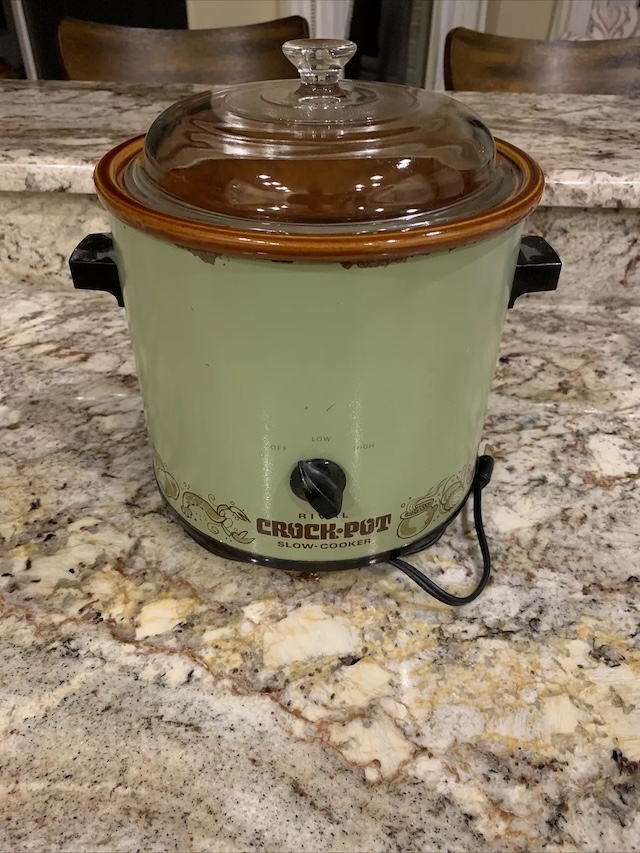 This timeless Rival Crock-Pot, sitting on a kitchen counter, evokes memories of slow-cooked family meals and hearty stews