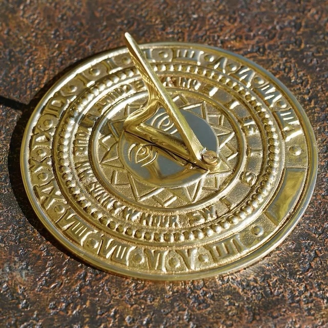 A beautifully detailed sundial casting shadow to indicate the time of day. Its intricate carvings represent a bygone era when this was a primary tool for timekeeping