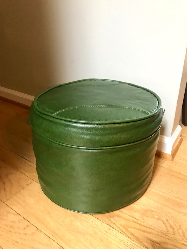 This vintage green ottoman pouffe, with its classic round design, is a perfect reminder of cozy living rooms from past decades. Compact, stylish, and oh-so-practical!