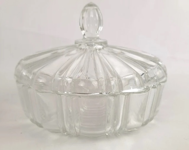 A closer look at the vintage glass candy dish, with its intricate ribbed design and knobbed lid, crafted to keep precious sweets hidden… albeit not too quietly!