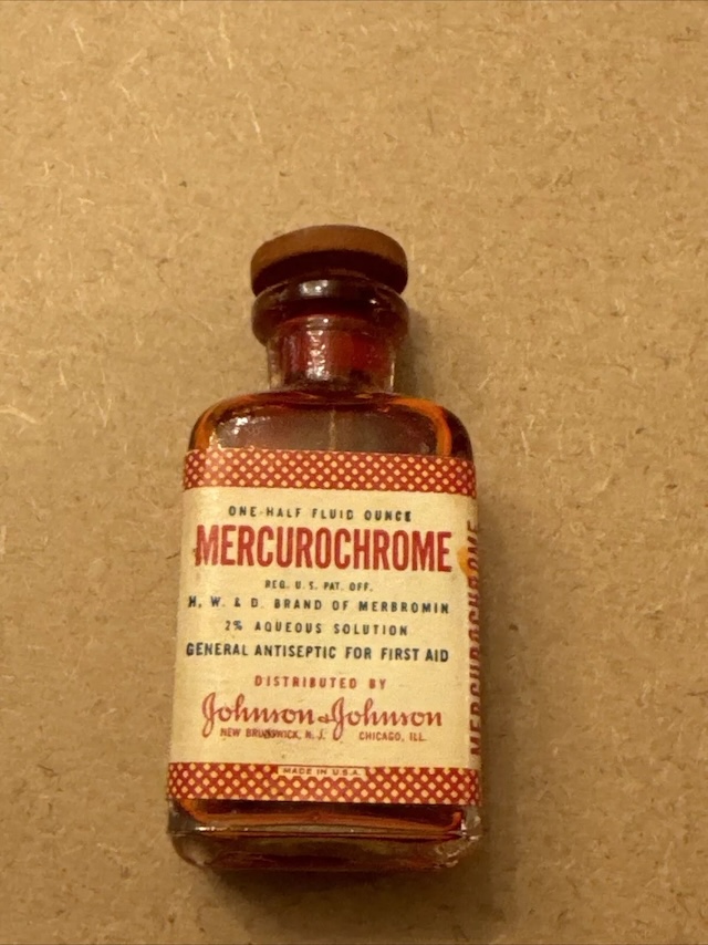 A close-up of a well-preserved vintage bottle of Mercurochrome from Johnson & Johnson, showcasing its glass stopper and iconic red solution inside