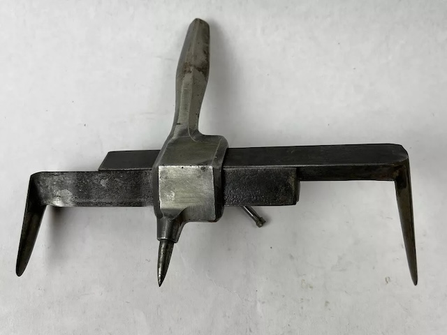 This antique gasket cutter features a metal cutting arm with adjustable parts, making it versatile for different cutting needs