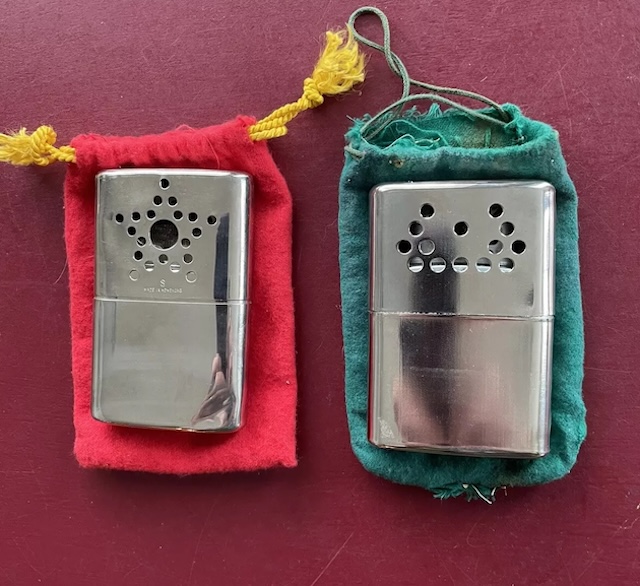 Two vintage hand warmers with their original pouches, ready to keep your hands toasty in the cold.