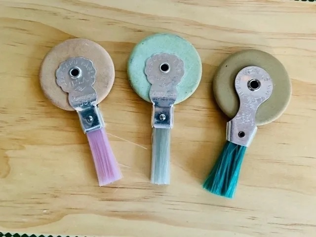 Three colorful vintage typewriter erasers with brushes, each with a different colored handle—perfect for those who remember the classic clack of the typewriter keys