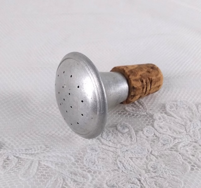 A close-up view of an aluminum vintage sprinkler bottle top, used to sprinkle water evenly on clothes for easier ironing