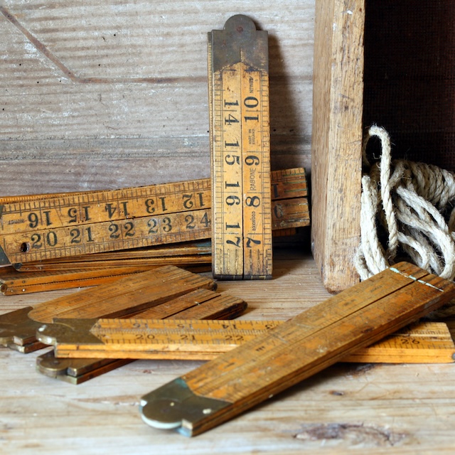 A variety of folding wooden rulers, each with its own unique markings from decades of use. Tools like these played a key role in precision work