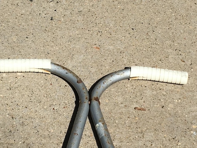 A close-up of the white, weathered handlebars. They show the marks of years of playful use, a reminder of the simple joys of childhood