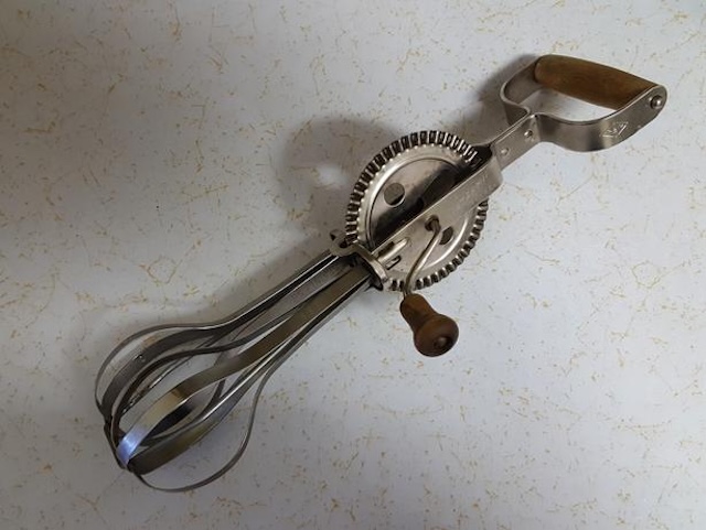 The smooth gear mechanism of this vintage hand-crank egg beater demonstrates the reliable manual design, perfect for whipping up eggs or batter