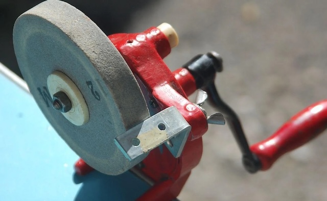 With its vibrant red color, this old-school hand crank grinder offers a nostalgic view into how craftsmen used manual power to achieve precise sharpening results