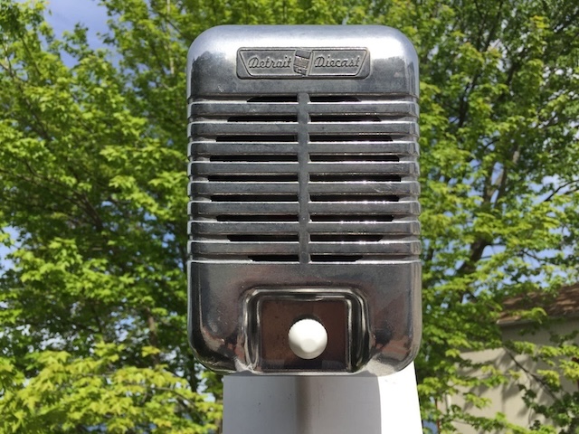 Standing tall against a backdrop of greenery, this classic vintage drive-in speaker is a reminder of the golden age of drive-in theaters